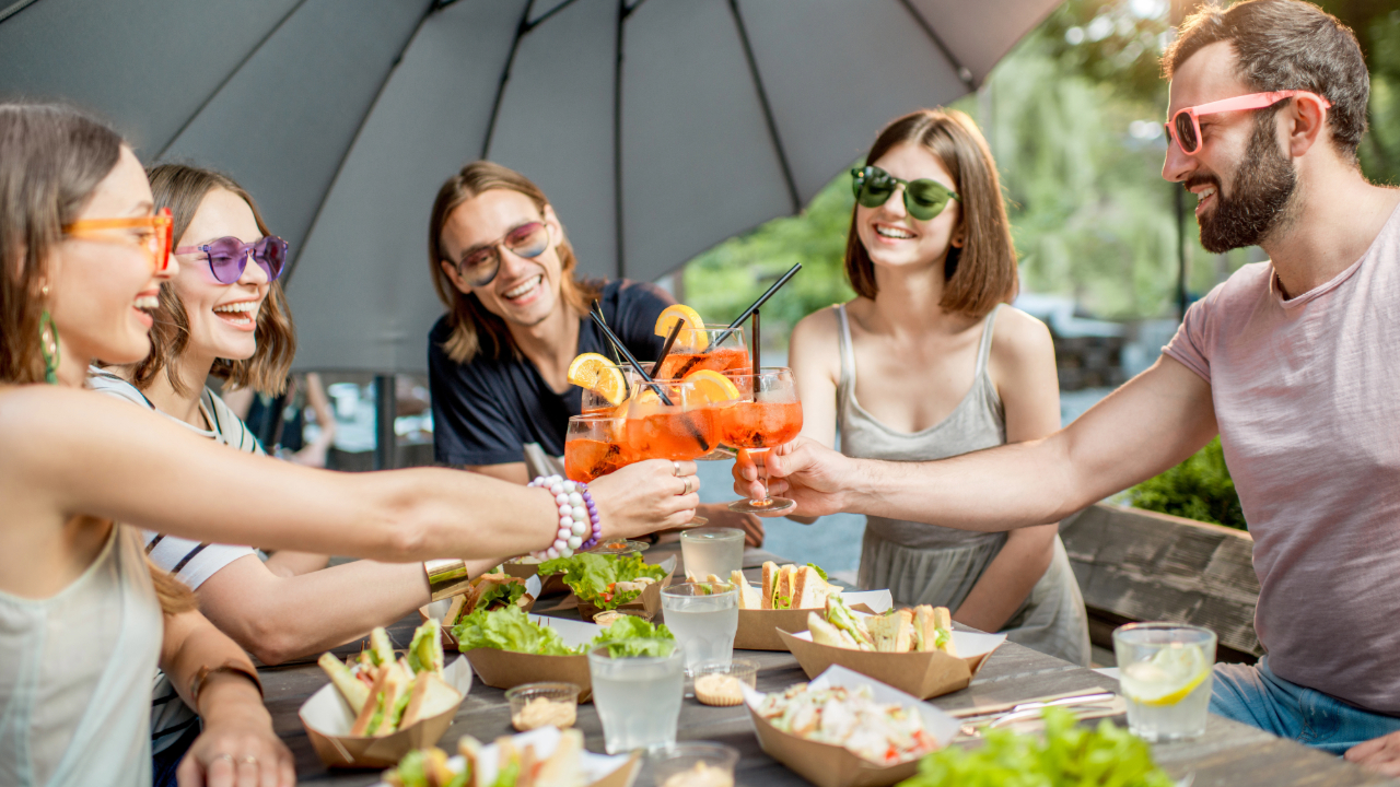 5 friends toasting with apéritifs outside with sandwiches