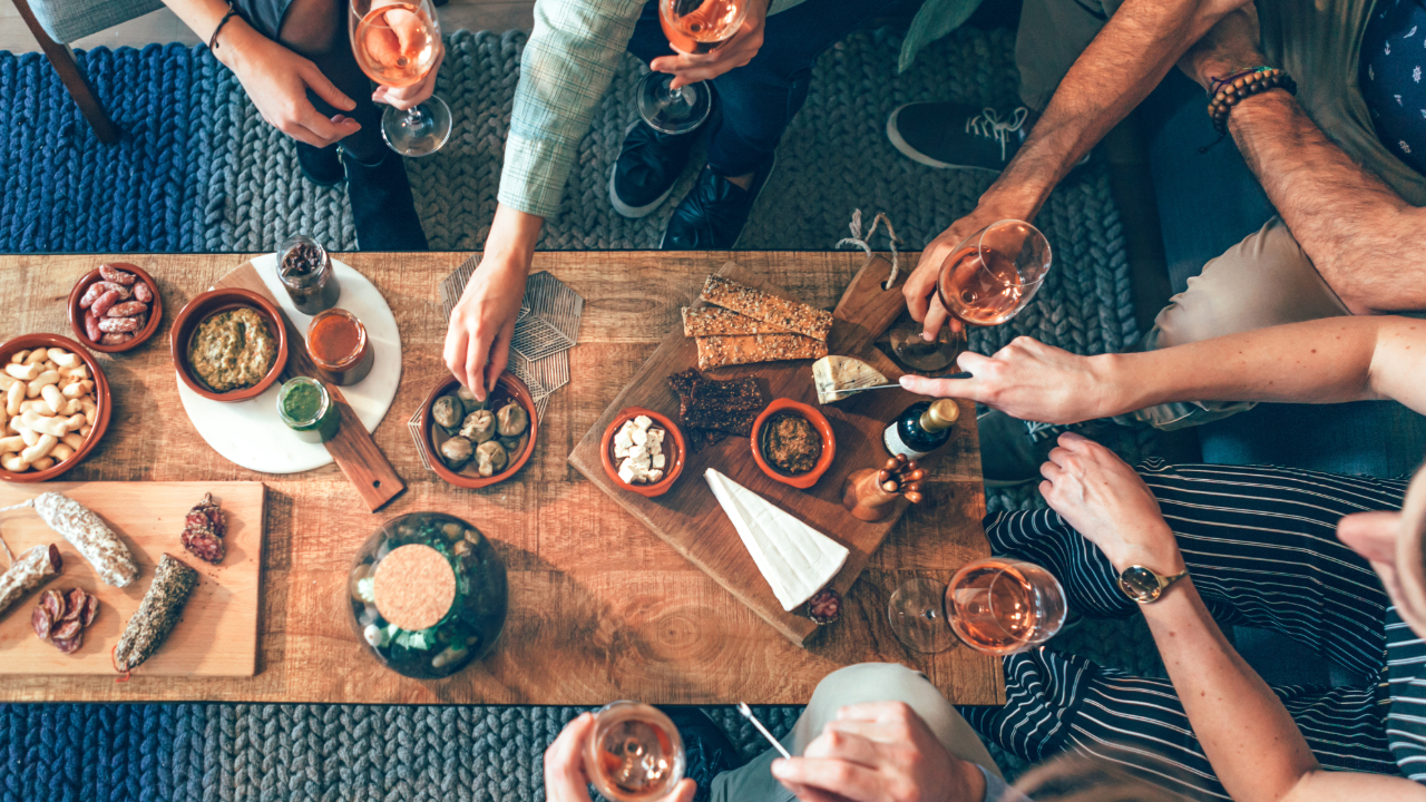 An overhead shot of friends at a table with aperitifs and food
