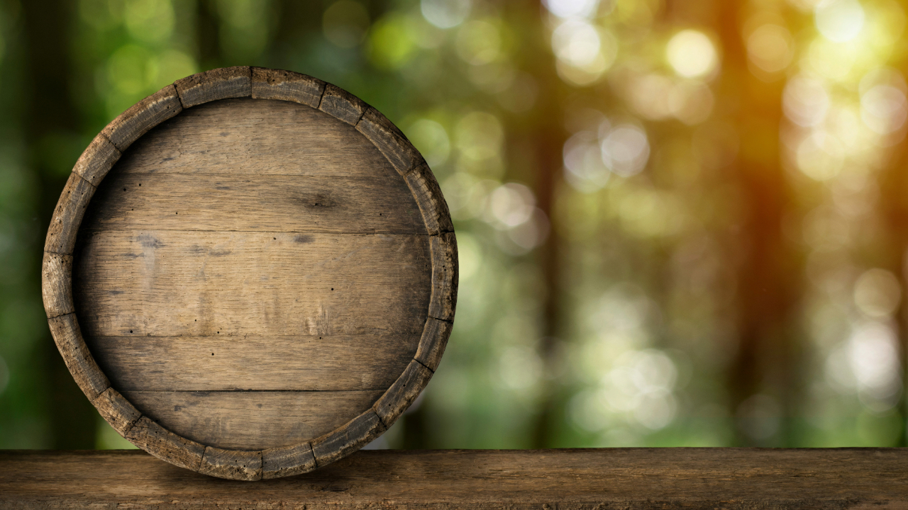 An old barrel for aging spirits in front of a blurred background of the woods