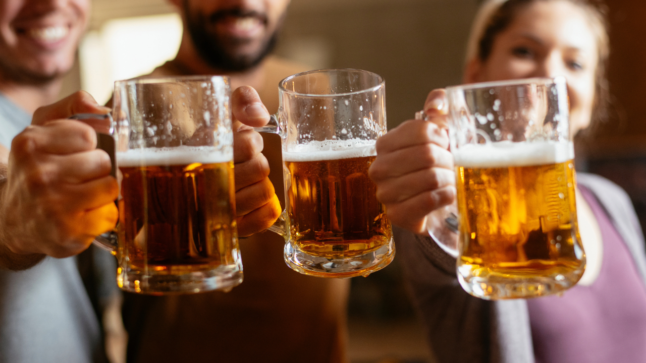 A group of 3 friends toasting with mugs of beer