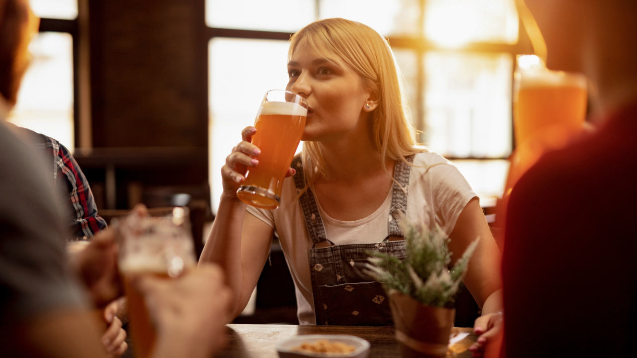 A woman in a rustic enjoying a tall glass of premium beer