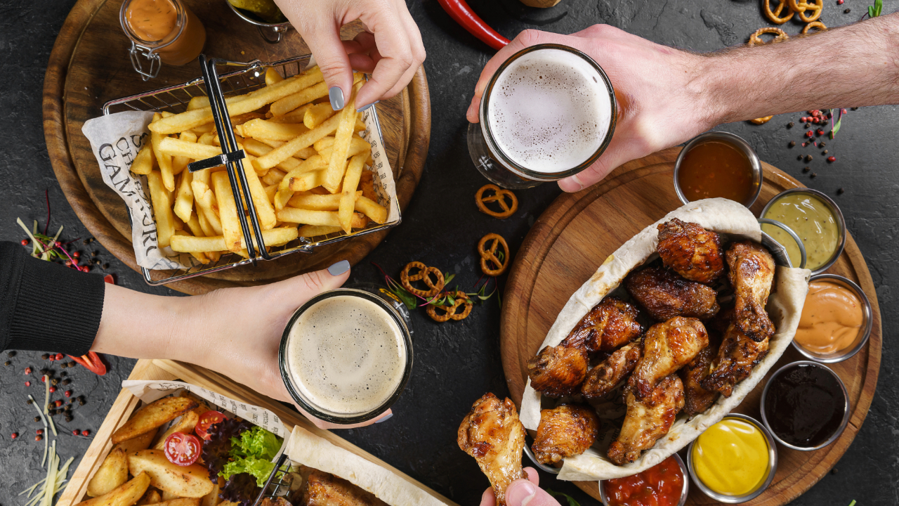 An over head shot of a table with beer, fries, chicken wings, and various food items
