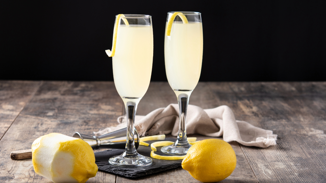 Two French 75 cocktails, one of the best bar drinks of 2024, on a bar with cut lemons and lemon garnishes