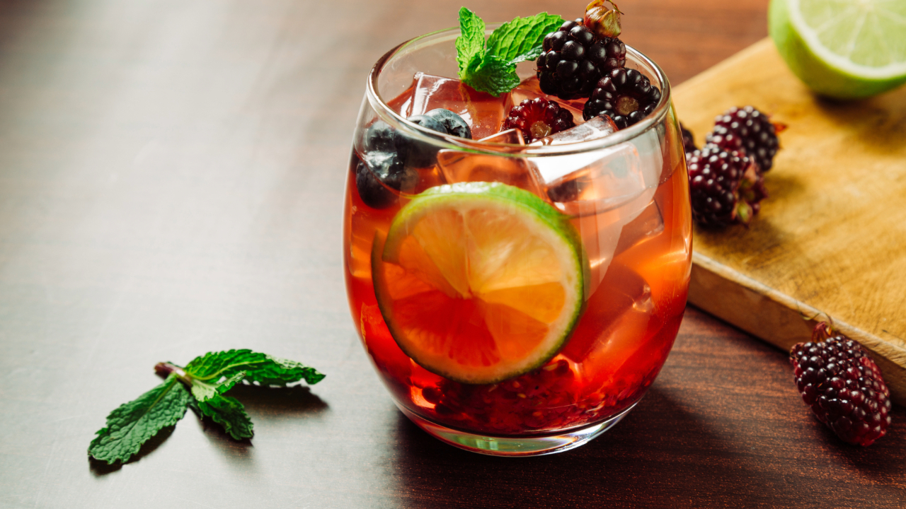 A cocktail with raspberries, limes, blueberries, and other fruit garnishes