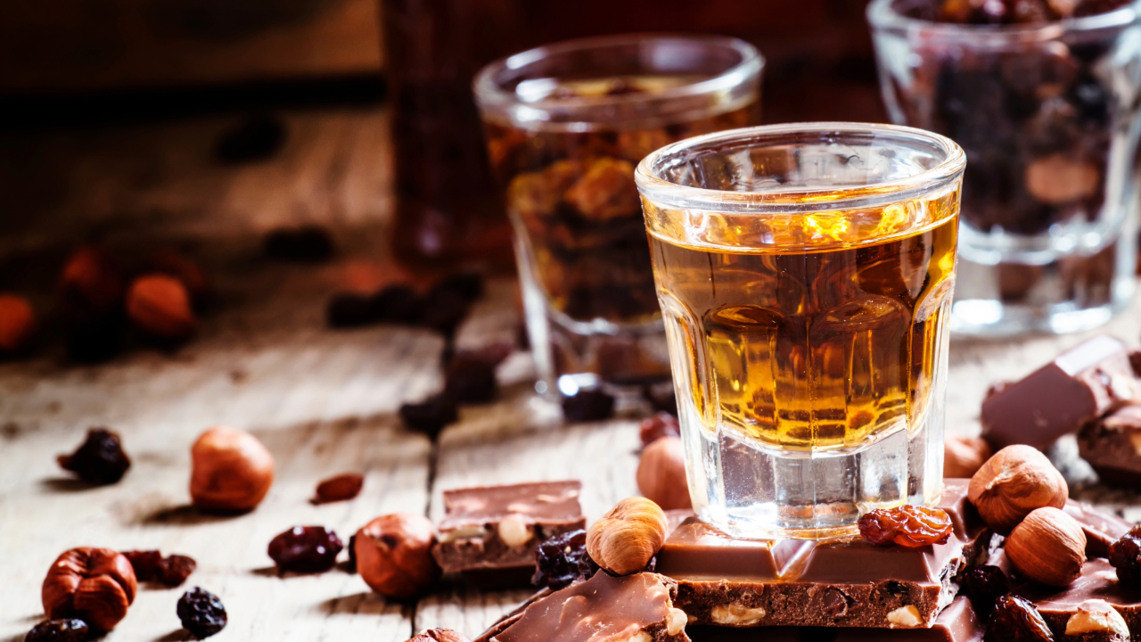 A glass of exquisite whiskey behind fine artisan dark chocolate