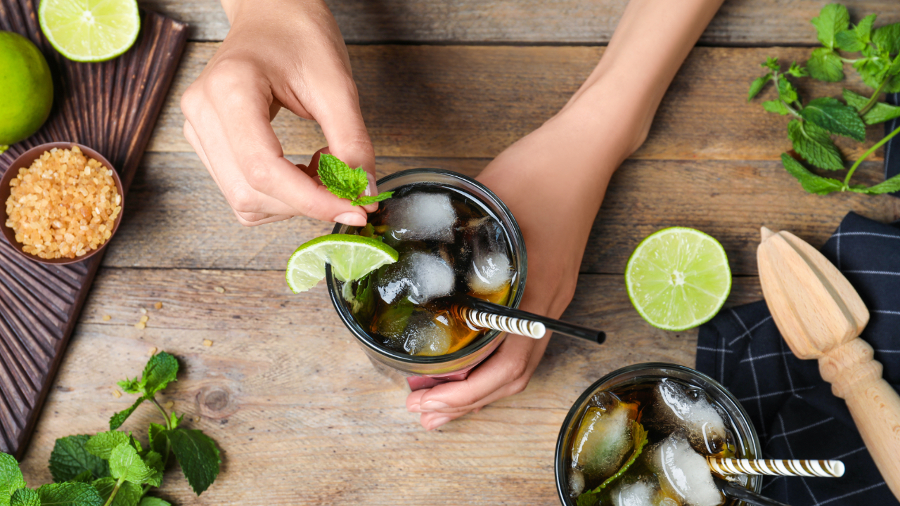 Overhead shot of hands putting garnishes on an elegant cocktail