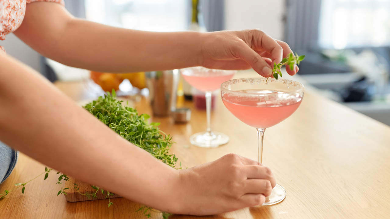 A close up of a woman's arms preparing spirits with garnishes in her fancy home bar