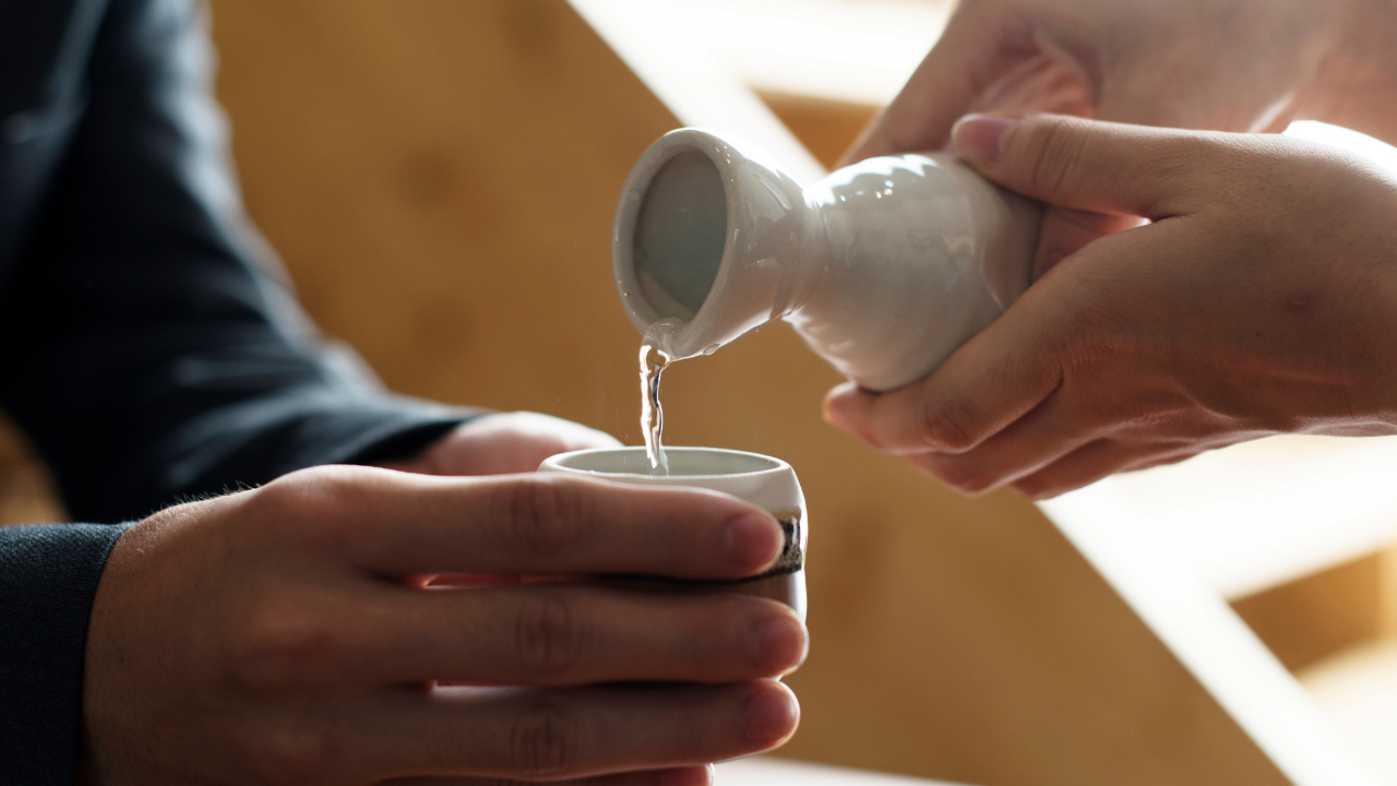 A close up of a sake bottle being poured into a cup