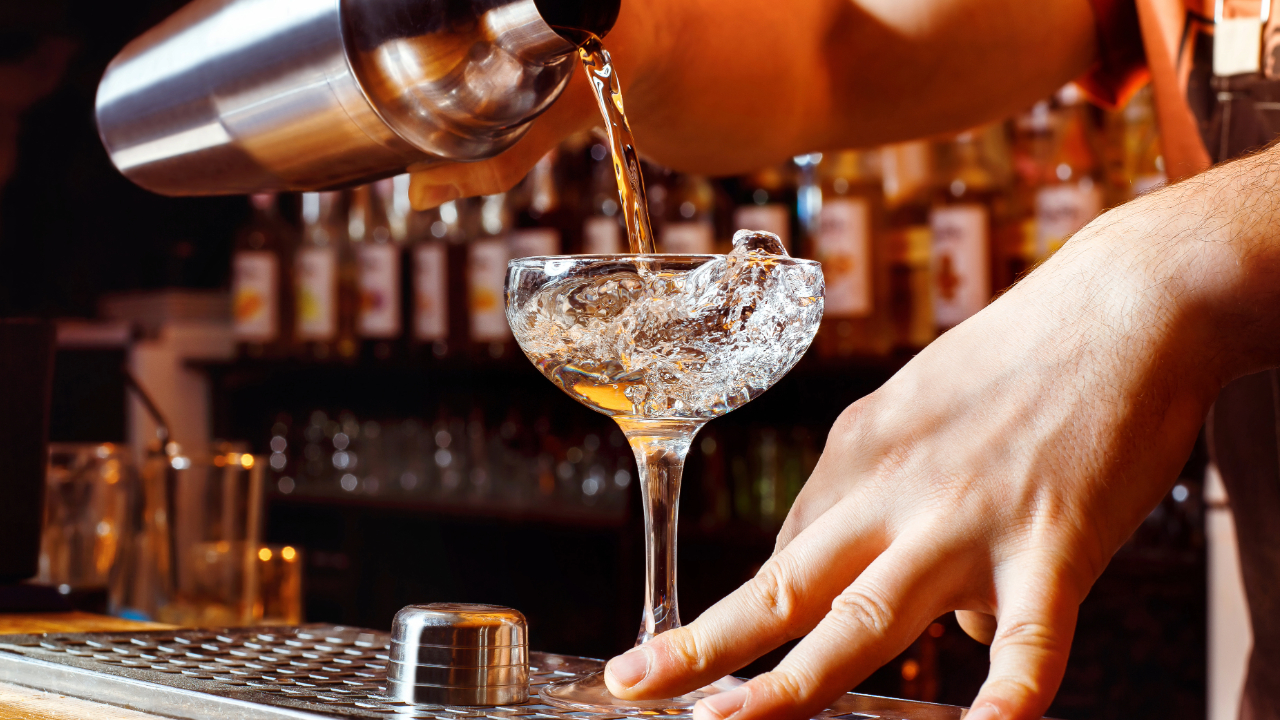 A close up of an elegant cocktail being poured at a classy bar