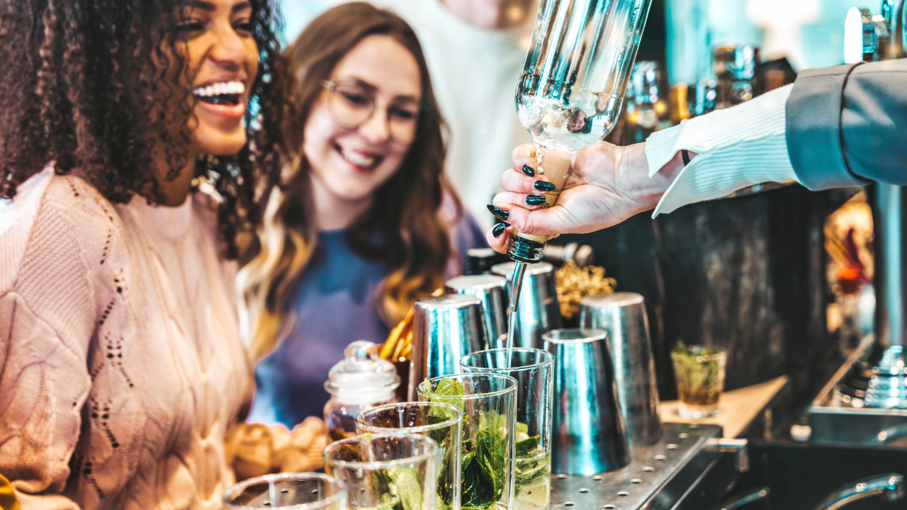 Two friends enjoying drinks poured by a professional mixologist