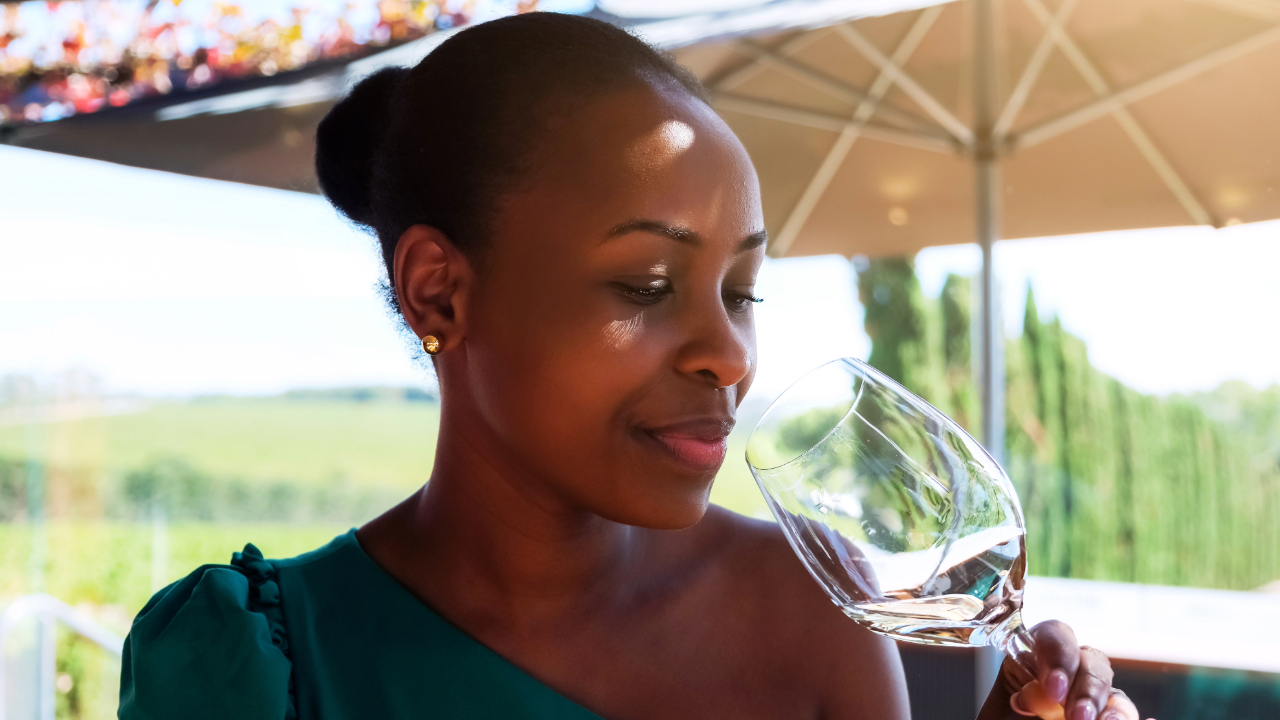 A woman in an elegant vineyard swirling a glass of premium white wine